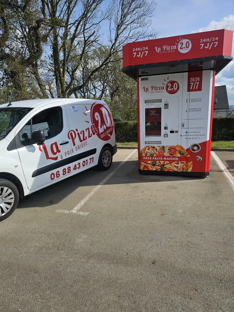 Le distributeur de pizzas La Pizza 2.0 de Plomodiern, au soleil, avec la camionnette de la maison garée devant